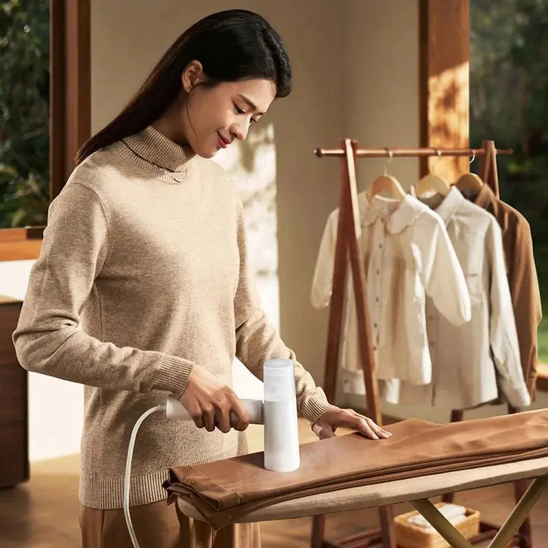 Woman ironing a piece of fabric in a room with clothes on hangers in the background